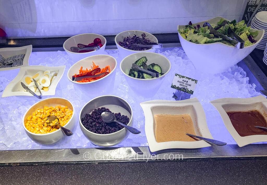 A salad bar with bowls of vegetables such as lettuce, corn, carrots, etc. placed on ice.