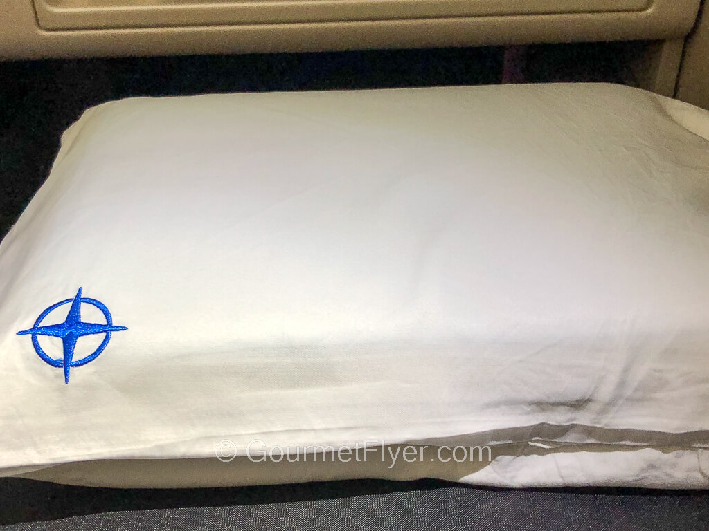 A gel pillow is placed in a white pillowcase with a star shaped logo on its lower left corner.
