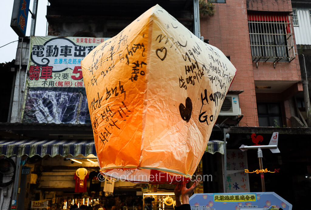 A paper lantern lit with fire inside and wishes written on the outer shell is released into the air.