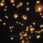 The Pingxi Sky Lantern Festival features hundreds of lanterns being released at the same time, appearing in the sky as bright orange spots.