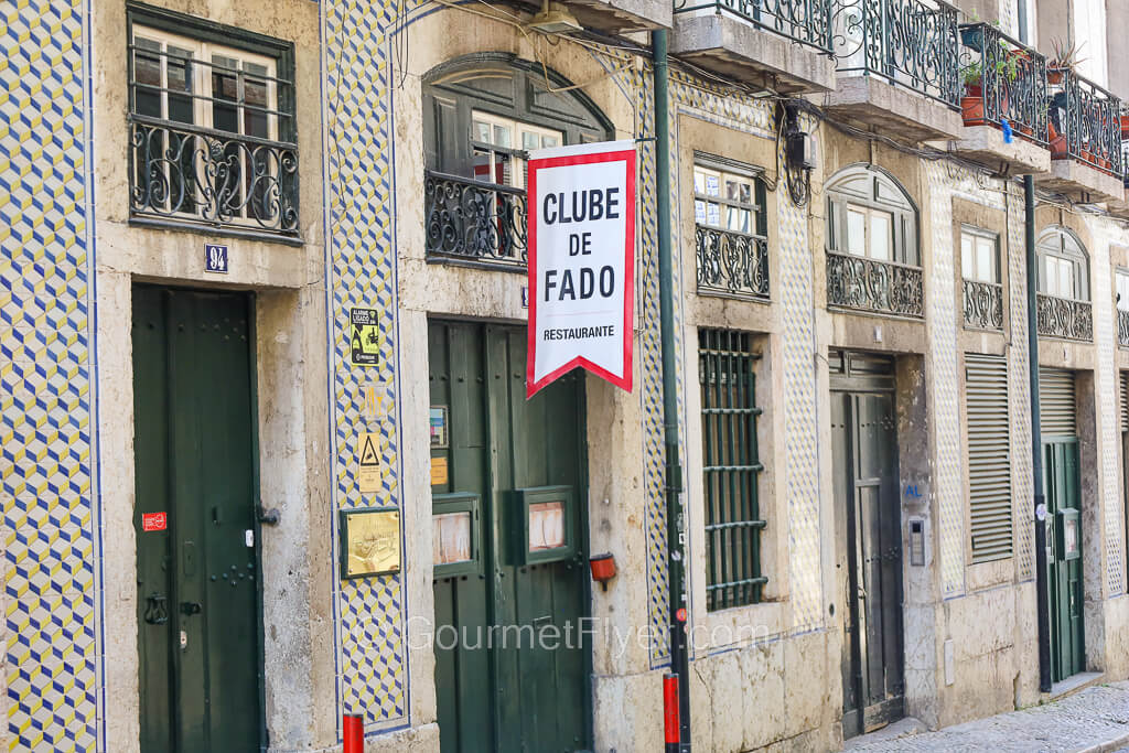 The facade of a traditional Portuguese building with a "Clube de Fado" banner hanging above its front door.
