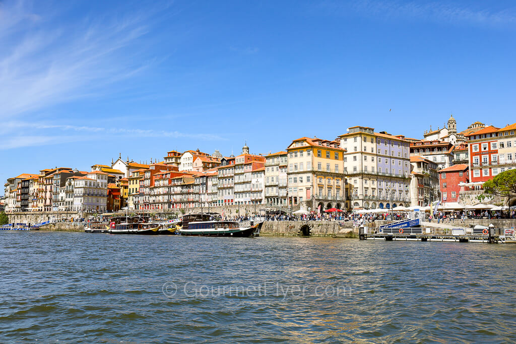 Vibrant traditional buildings with pastel color facades line the waterfront of a river.