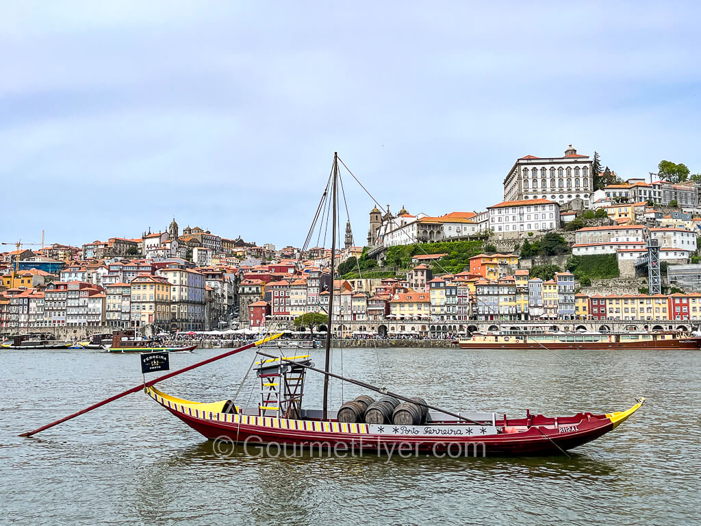 A sailboat rests on the river with the colorful landscape of Porto in the background.
