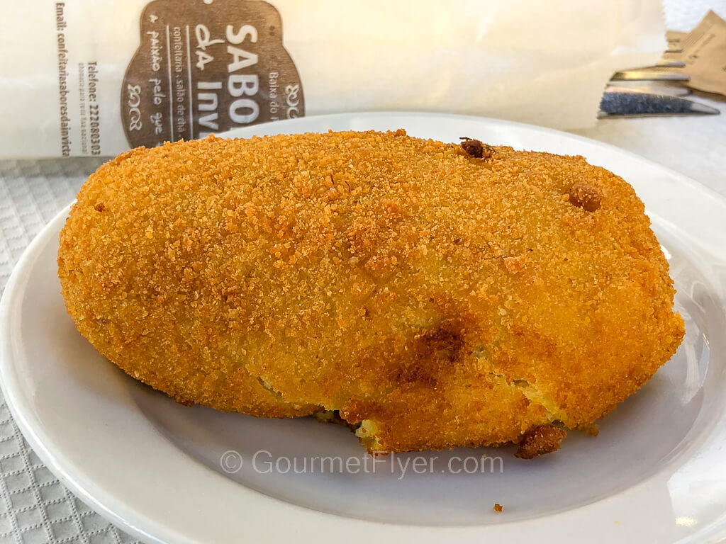 A golden brown oblong shaped fired pastry has a bread crumb like texture on its shell.