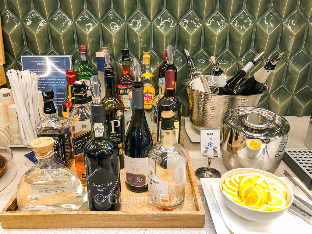 A bar setup with many bottles of different liquors is placed alongside a bucket of wines on top of a counter.