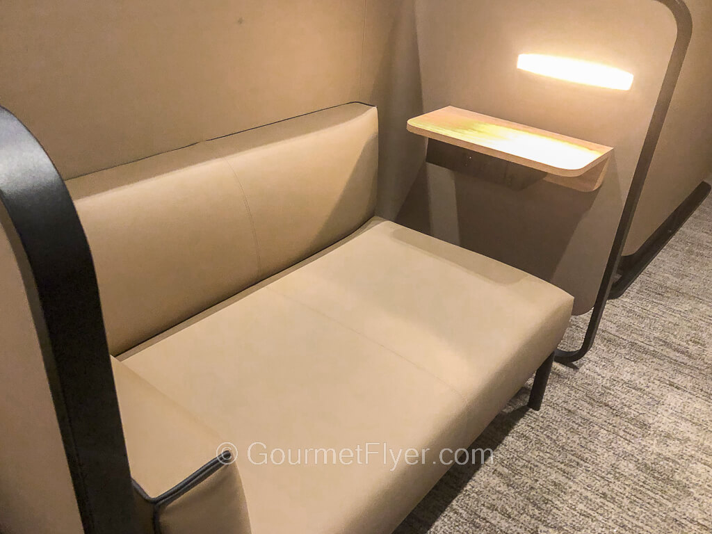 A long sofa enclosed in a cubicle-like space is fitted with a small desk and reading lamp.