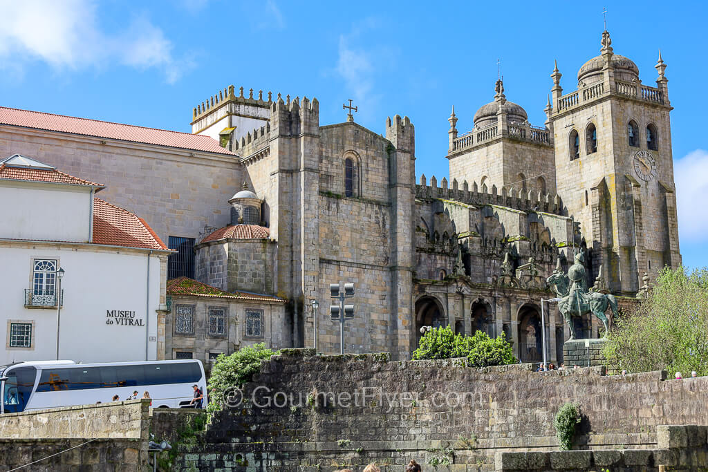 A small building on the left with a white facade is attached to a cathedral with a stunning and commanding architecture.