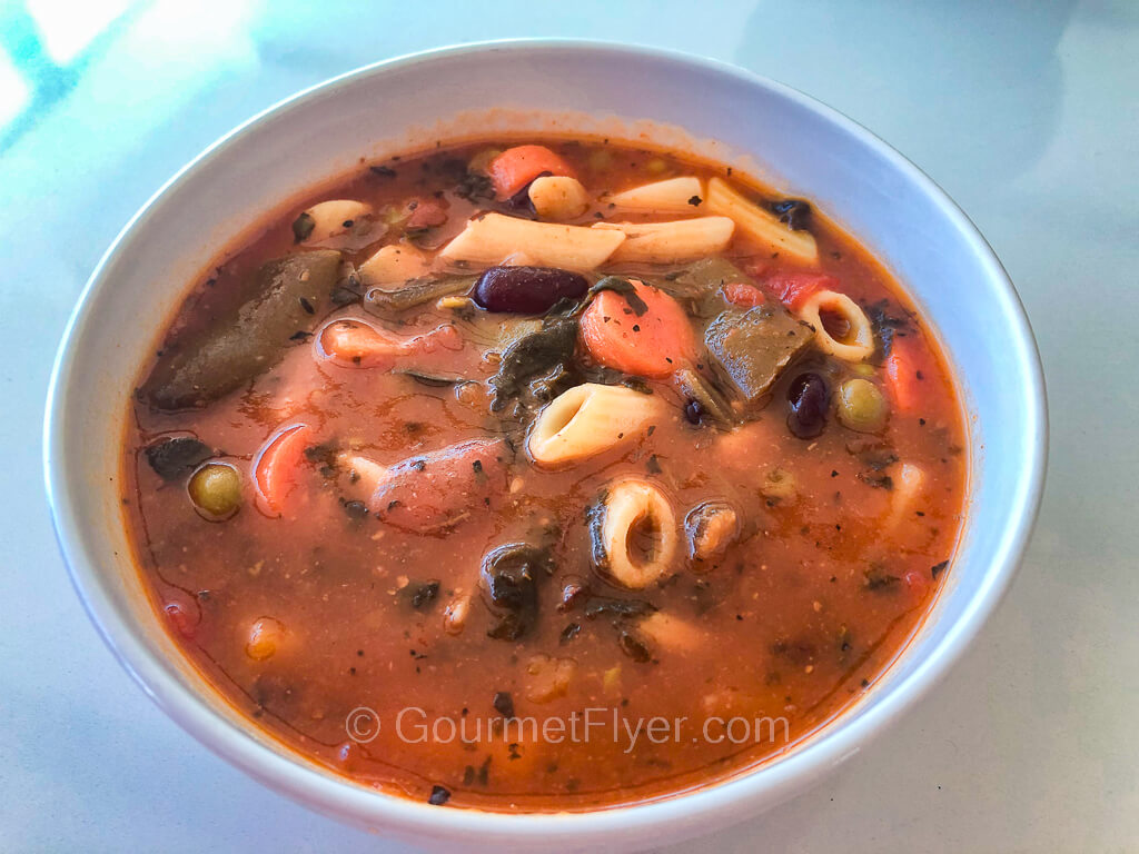 A vegetable soup contains a blend of diced veggies and pasta.