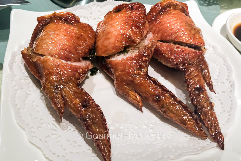 A plate of three fried chicken wings has their mid-joint section split in half.