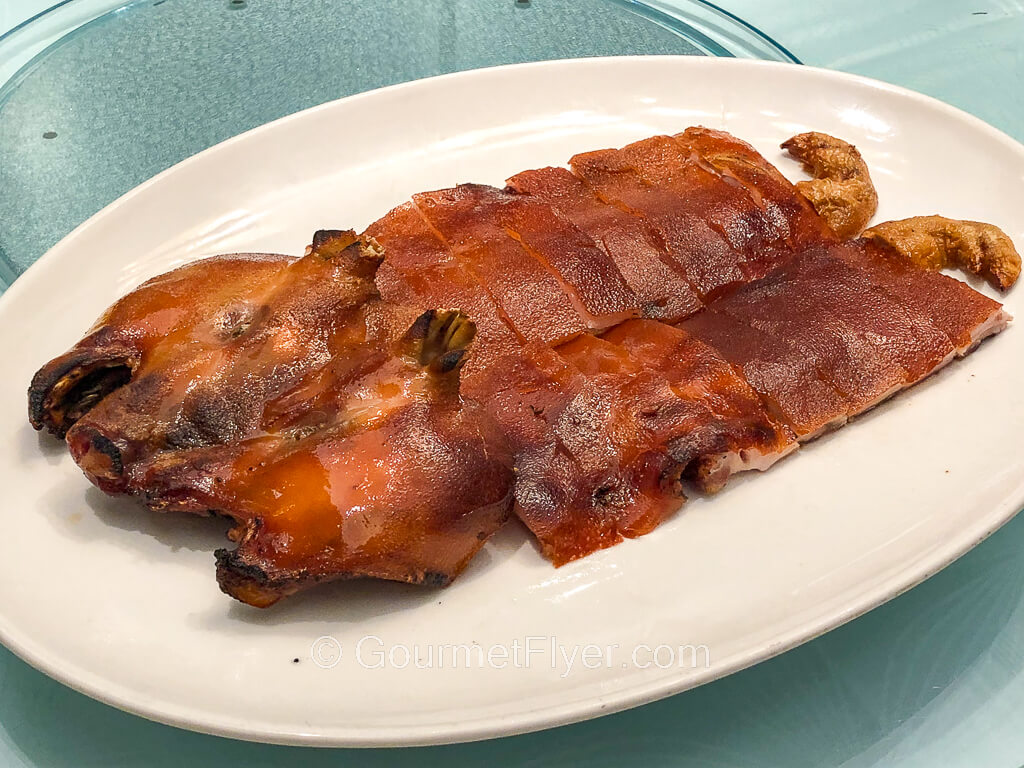 A whole cutup suckling piglet is served on a platter with its crispy skin facing upward.