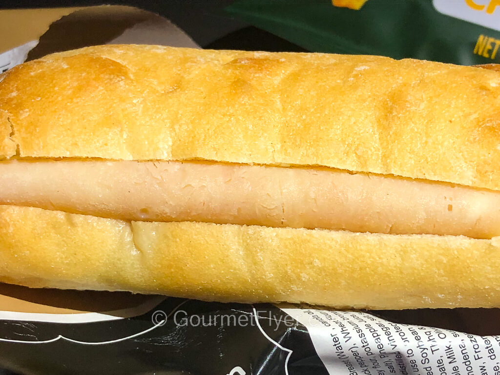 A closeup of a chicken submarine sandwich shows a piece of white meat folded in a roll.