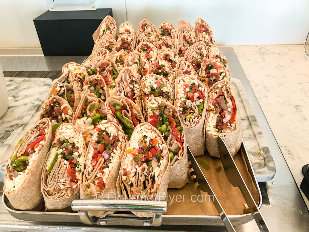 A large tray is filled with veggie wraps made with flour tortilla cut in halves and presented vertically, displaying the ingredients.