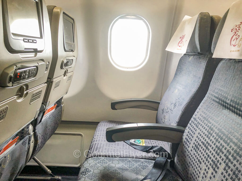 Two airplane seats are on the right window side, with the seat back screens in front of them.