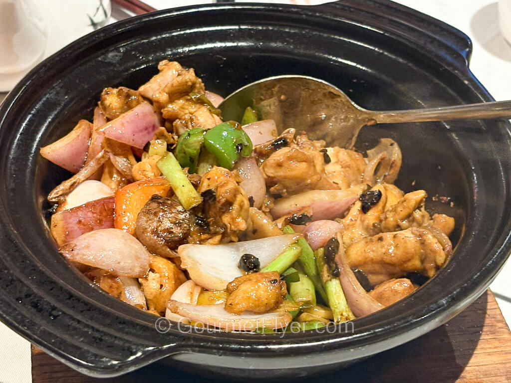 Pieces of chicken are blended with black beans, peppers, onion, and scallions in a casserole.