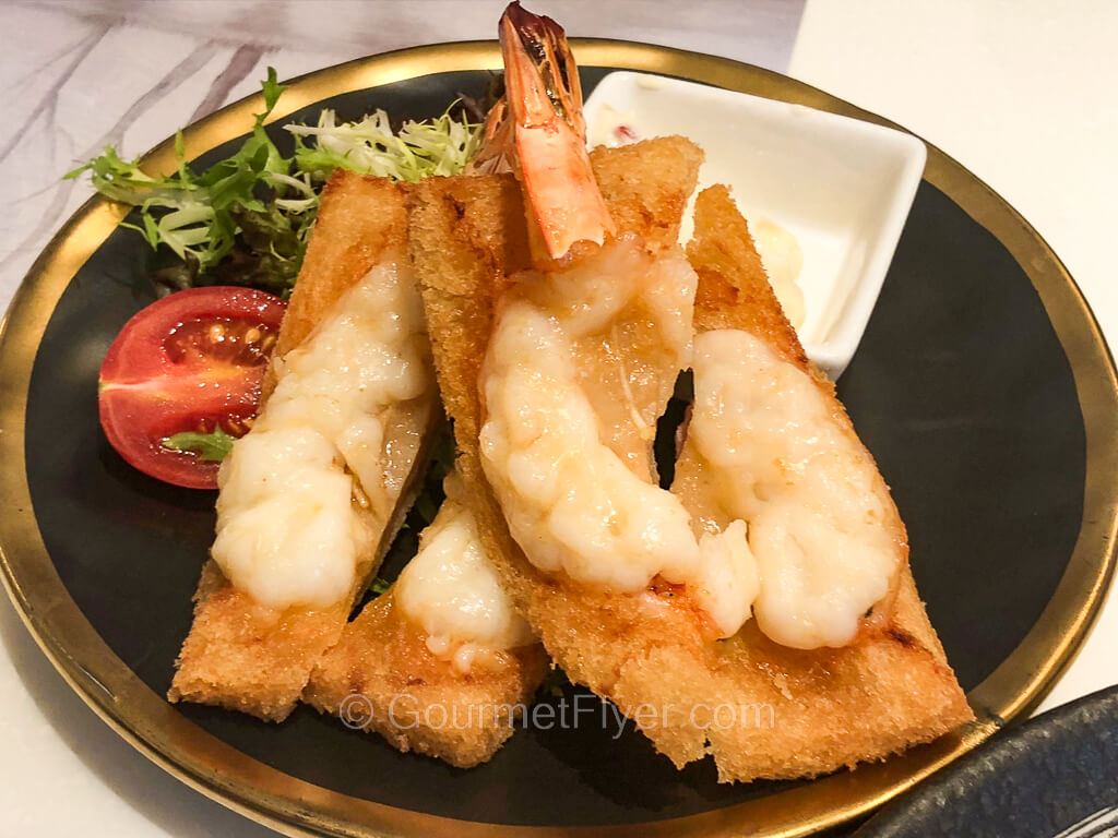 Deep-fried golden-brown toasts are topped with a large shrimp split in halves.