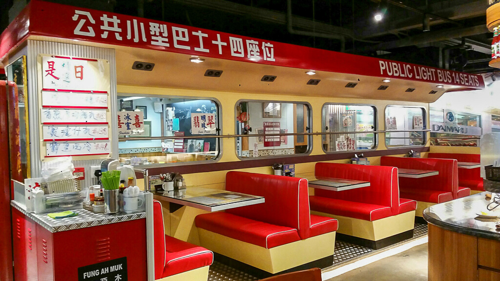 Booths at a restaurant with red seats and windows that look like the interior of a public minibus.