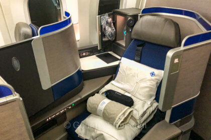 United's Polaris Business Class review features a standalone lie-flat seat with a pile of amenities placed on it.