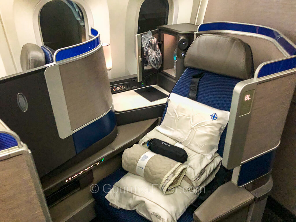 United's Polaris Business Class review features a standalone lie-flat seat with a pile of amenities placed on it.