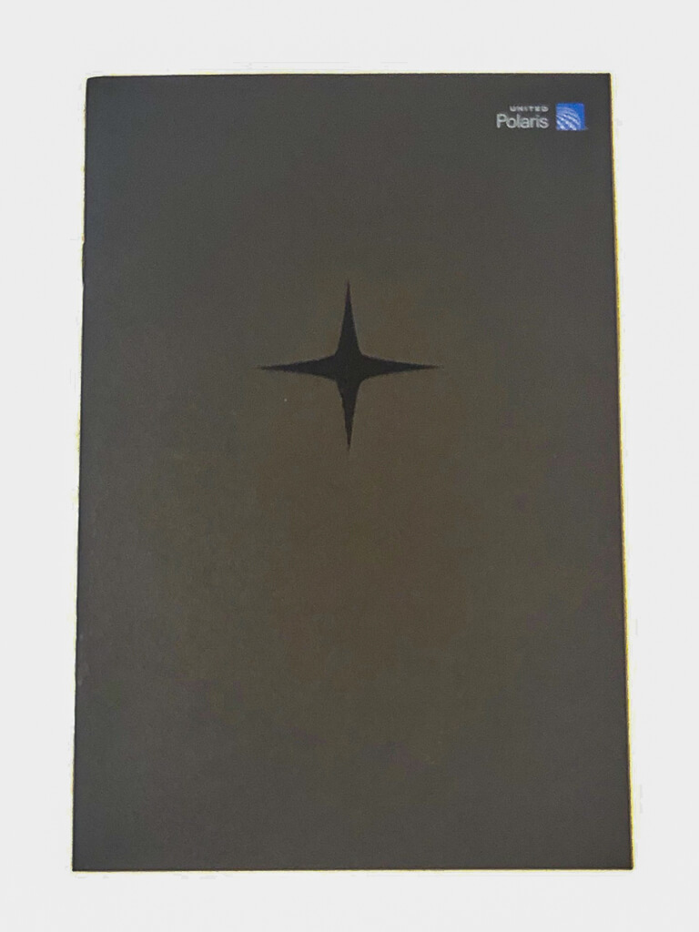 A rectangular dark booklet has a star logo imprinted on the front.