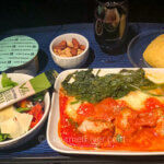 United's regional signature cuisines feature a dish of meatballs in tomato sauce accompanied with a salad, roll, and dessert in a cup.