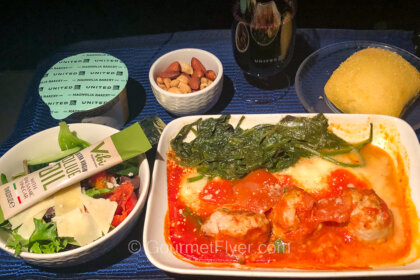 United's regional signature cuisines feature a dish of meatballs in tomato sauce accompanied with a salad, roll, and dessert in a cup.