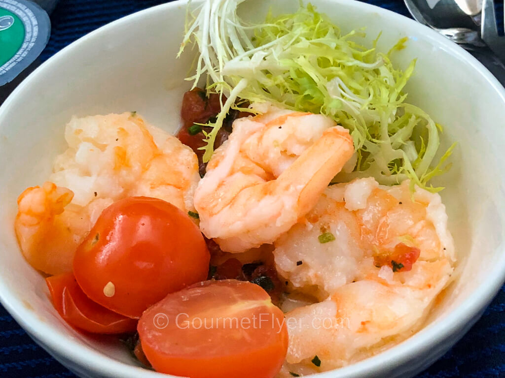 Three large, deshelled prawns are accompanied by a small green salad and cherry tomatoes.