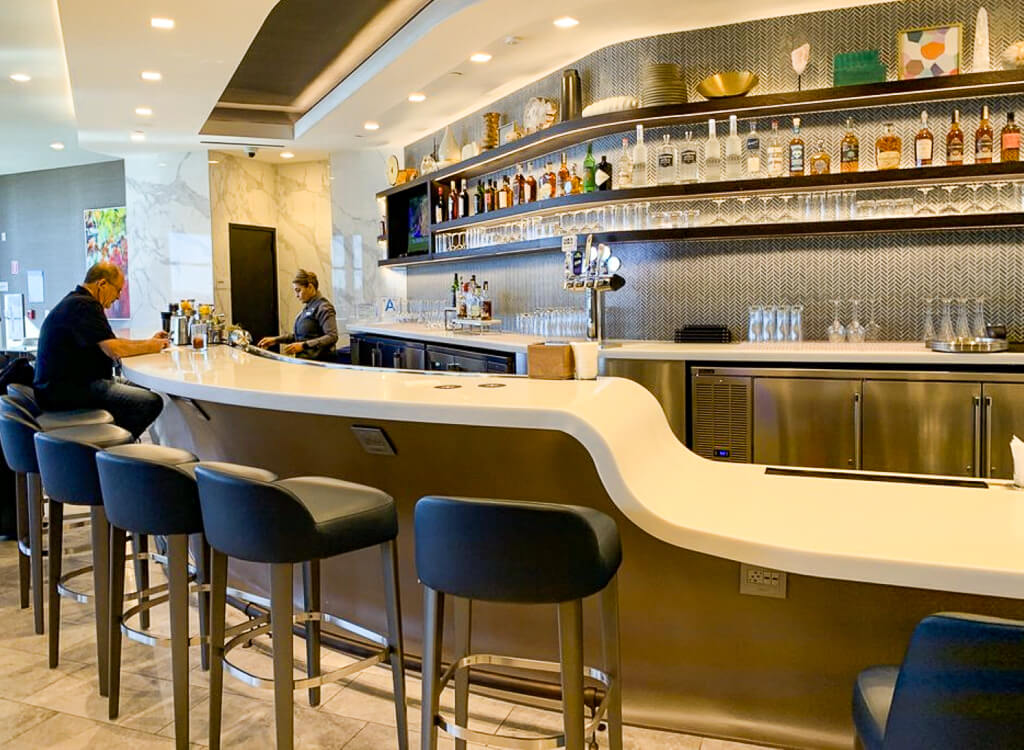 A lone customer sits at a bar with several empty stools enjoying a drink.