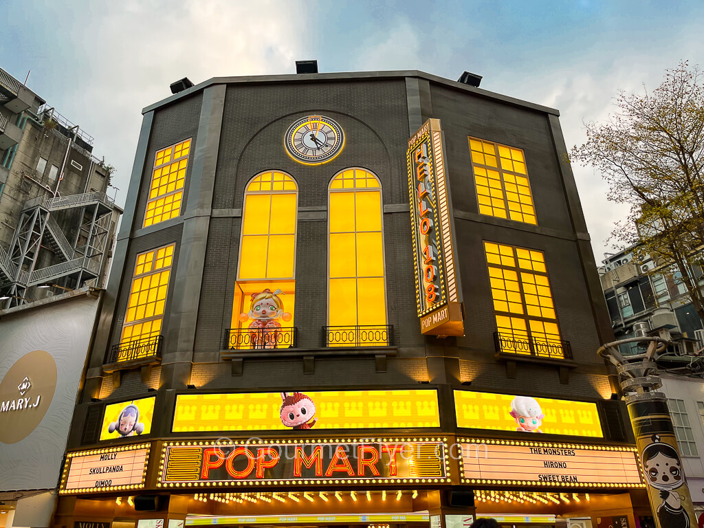 The exterior of a building has the look of a movie theater with large and brightly lit yellow windows.