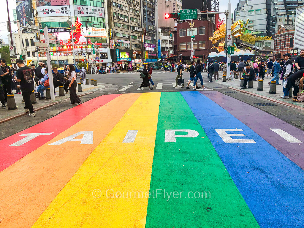 A crosswalk with stripes in rainbow colors with the name "Taipei" inscribed on it.