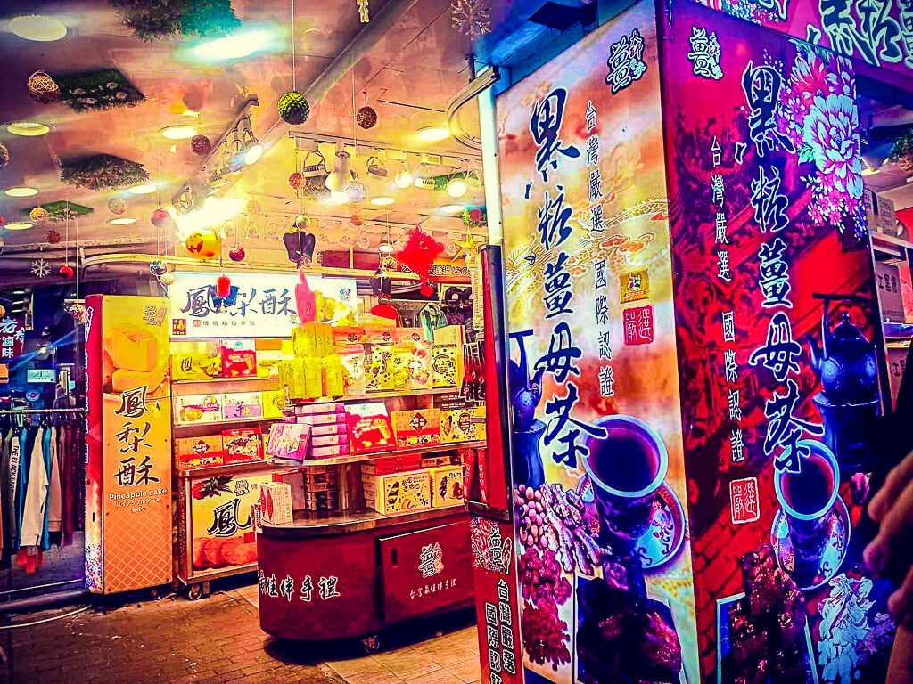 The colorful interior of a souvenir store has tall banners promoting its tea and pineapple cake products.