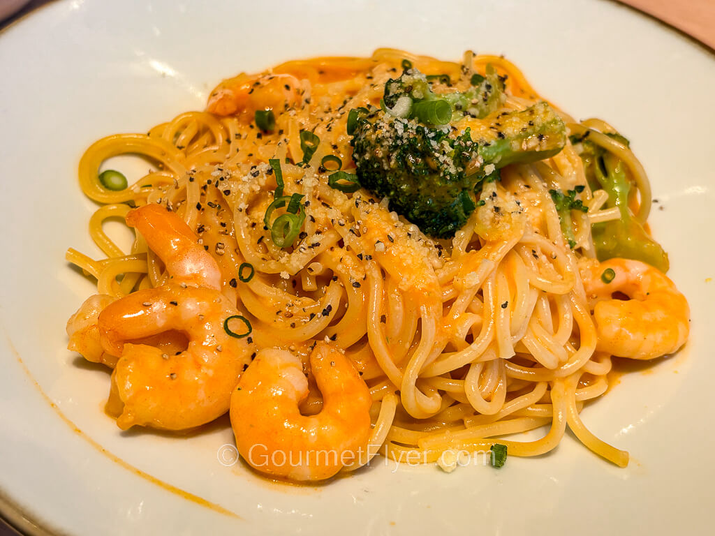 A plate of spaghetti is tossed in a red tomato-based sauce and garnished with shrimps and veggies.