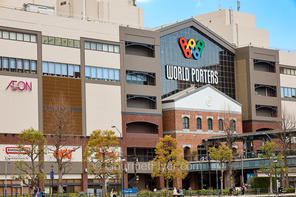 The exterior of a multi-story shopping mall has a large multi-color logo and the name World Porters.