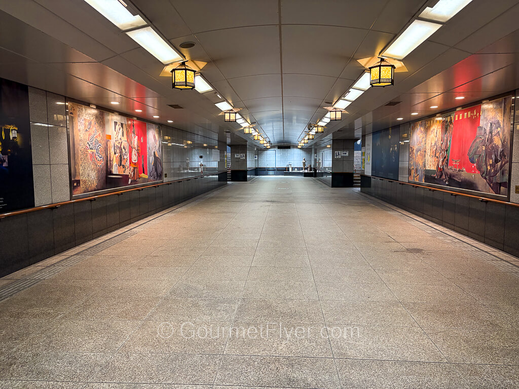 An underground pedestrian tunnel is decorated with artwork on both sides.