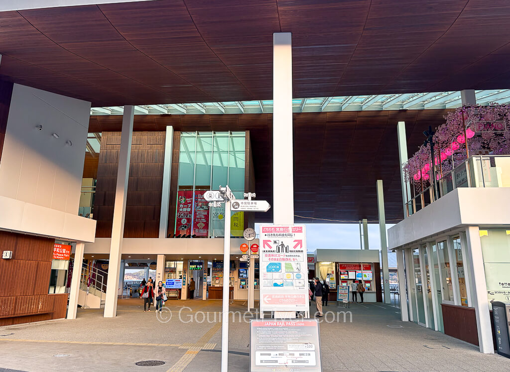 The front entrance of a ferry terminal has signs pointing to the left and right gates.