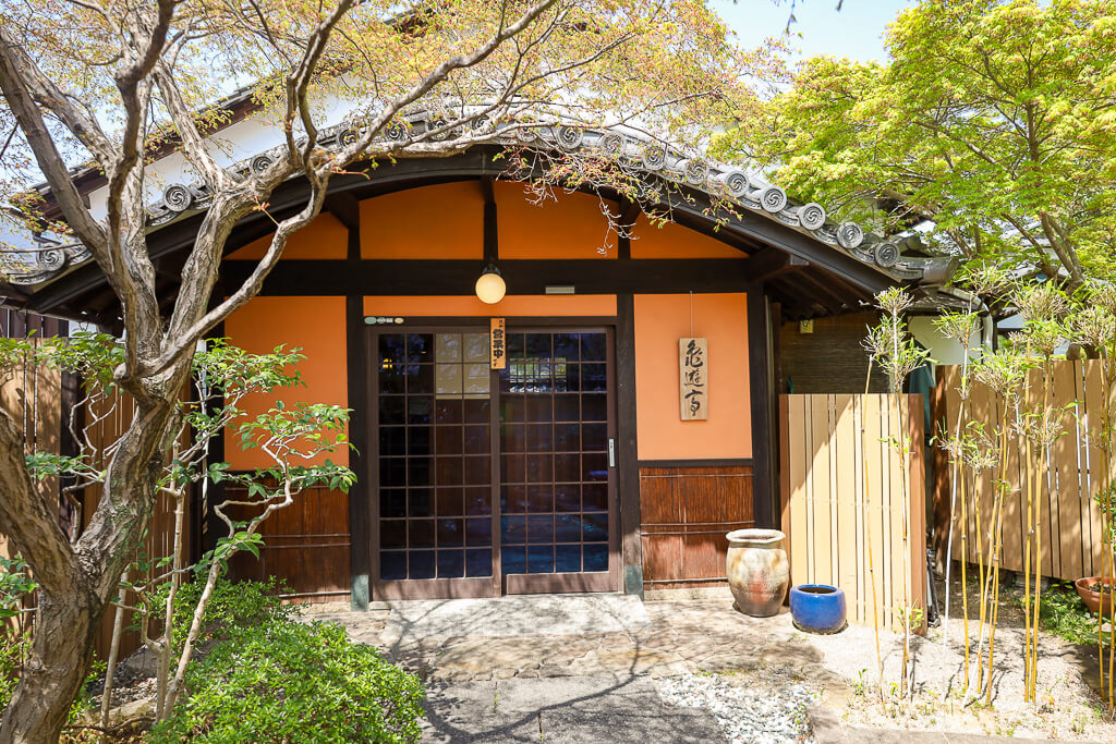 The front of a restaurant faces a courtyard with beautiful landscapes.