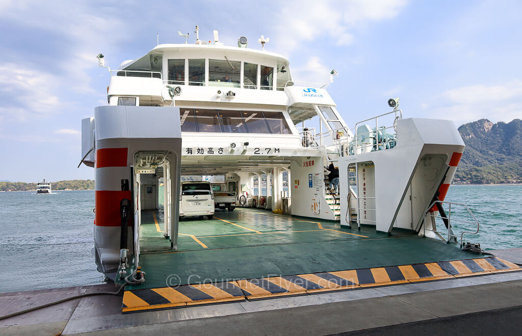 A ferry carrying vehicles on its lower deck has two passenger decks above it.