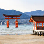 A day trip to Miyajima and Hiroshima features the Great Torii on the water off a corner of a shrine.