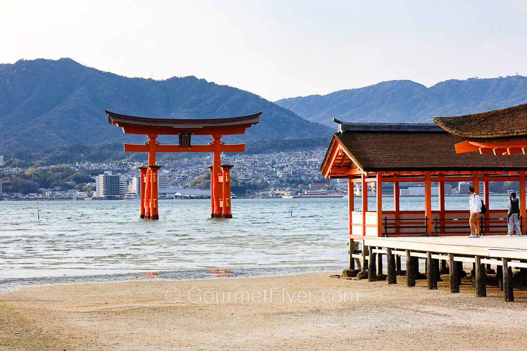 A day trip to Miyajima and Hiroshima features the Great Torii on the water off a corner of a shrine.