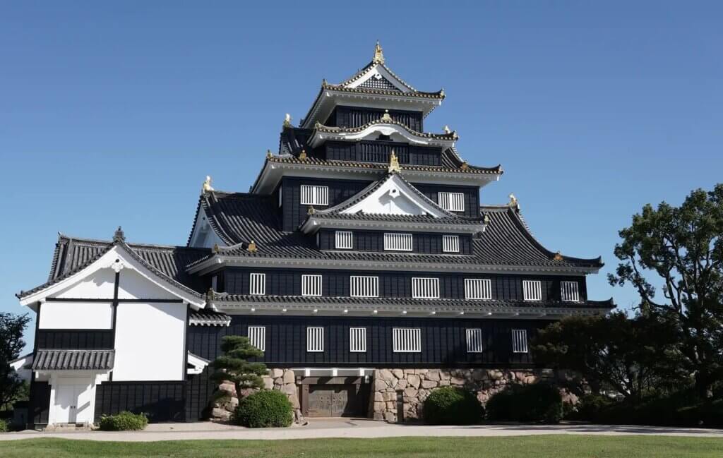 A Japanese castle under a blue sky has a black exterior wall.