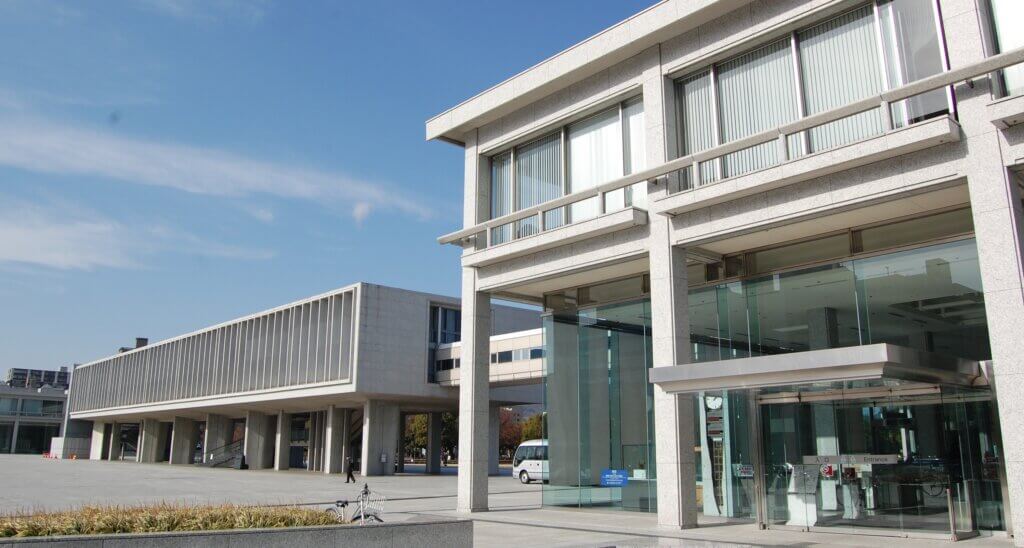 Two two-story buildings standing side by side are linked by a bridged walkway connecting their second floors.