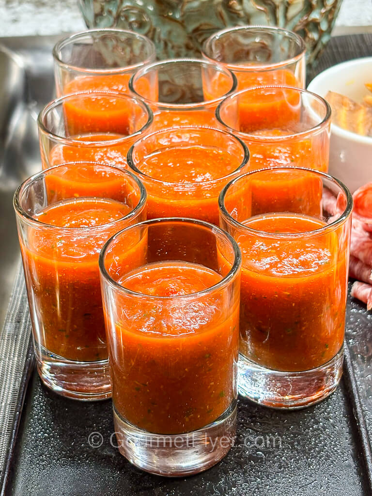 Tall glasses are filled with a tomato drink.