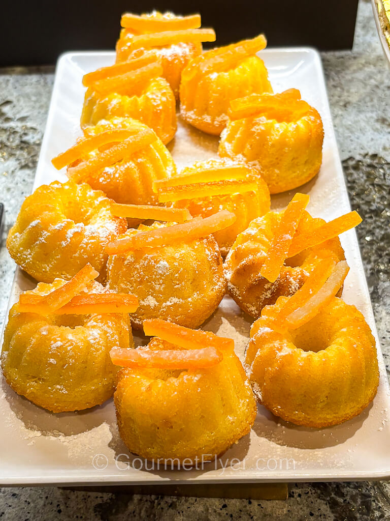 A platter of small orange desserts that look like cupcakes.