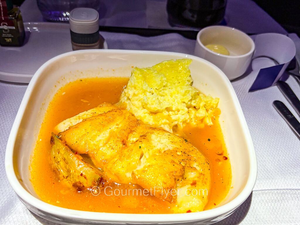 A filet of white fish is served with plenty of sauce and a side of risotto.