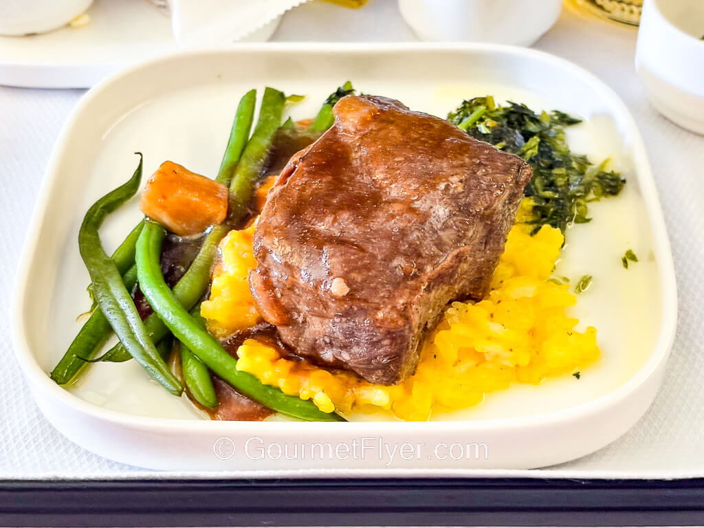A slab of beef sits atop a bed of yellow rice.