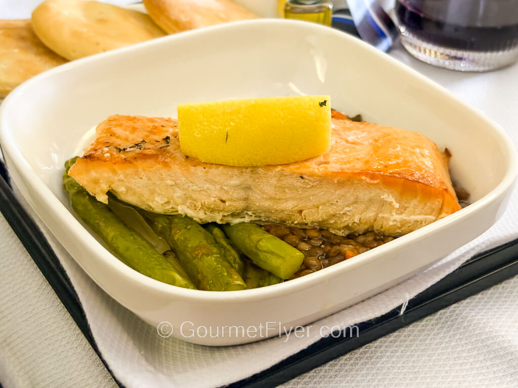 A piece of grilled salmon is garnished with a lemon wedge on top.