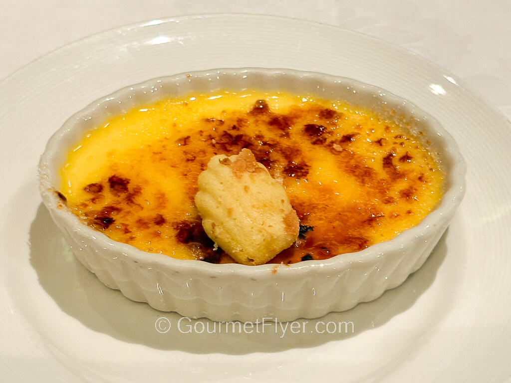 A Crème brûlée with a burnt top is served in a shallow dessert dish.