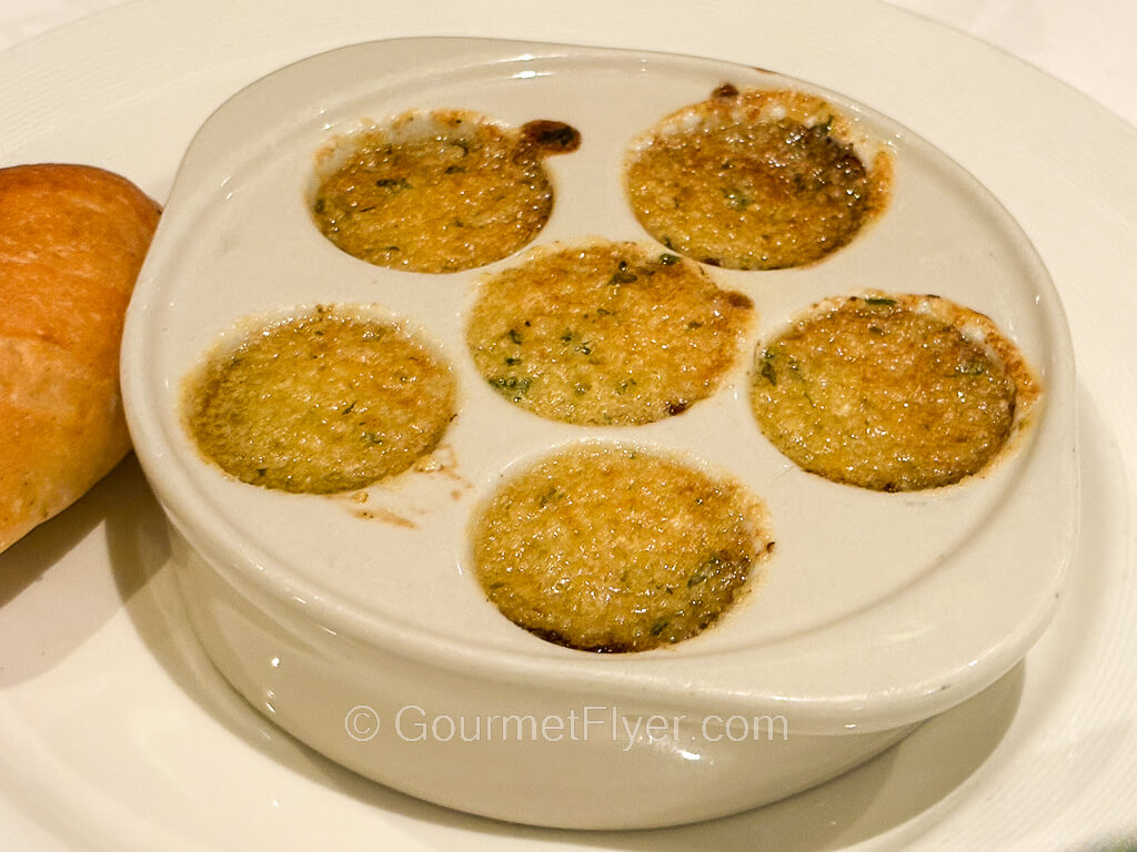 A six-holed dish is baked with melted cheese.