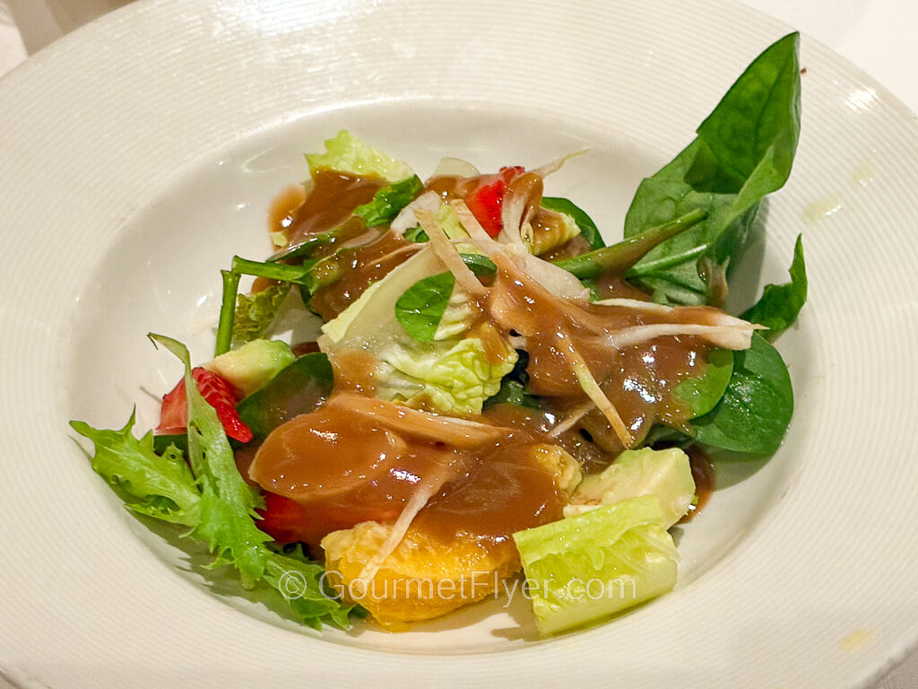 A green salad is served with a brown gravy-like dressing.