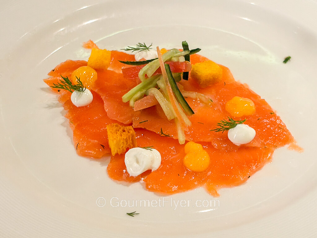 Thin slices of salmon are paired with pieces of croutons and a touch of cream.