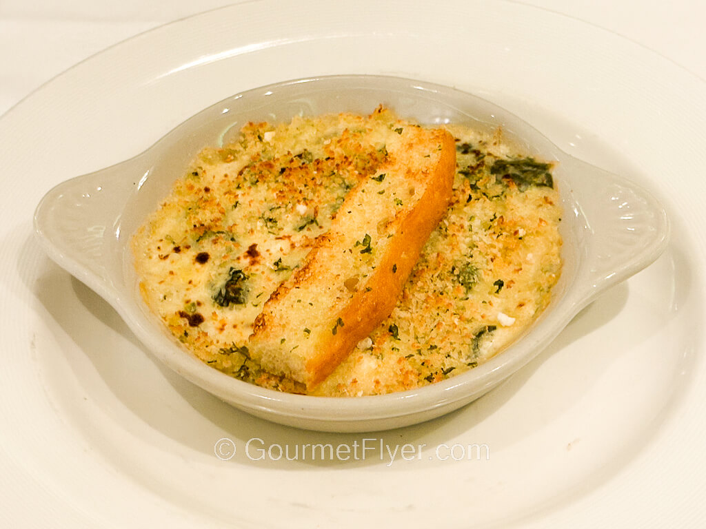 A baked cheesy looking dish is topped with a breadstick.